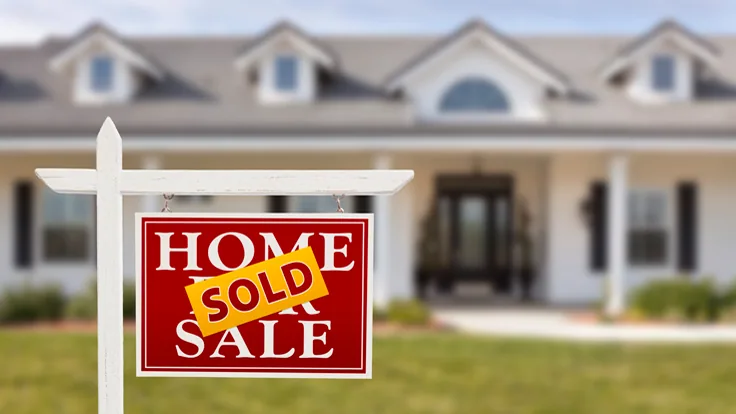 Home sold sign in front of single-story residential house with dormers and covered porch